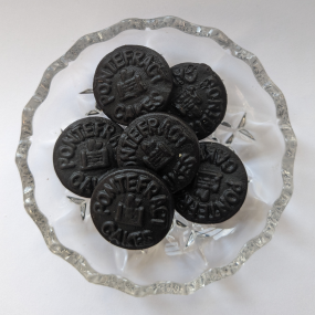 Black Pontefract cake sweets on glass dish