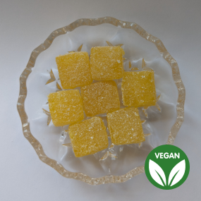 Yellow pineapple cube sweets on glass dish with vegan symbol