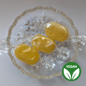 Yellow sherbet lemon sweets on glass dish with vegan symbol