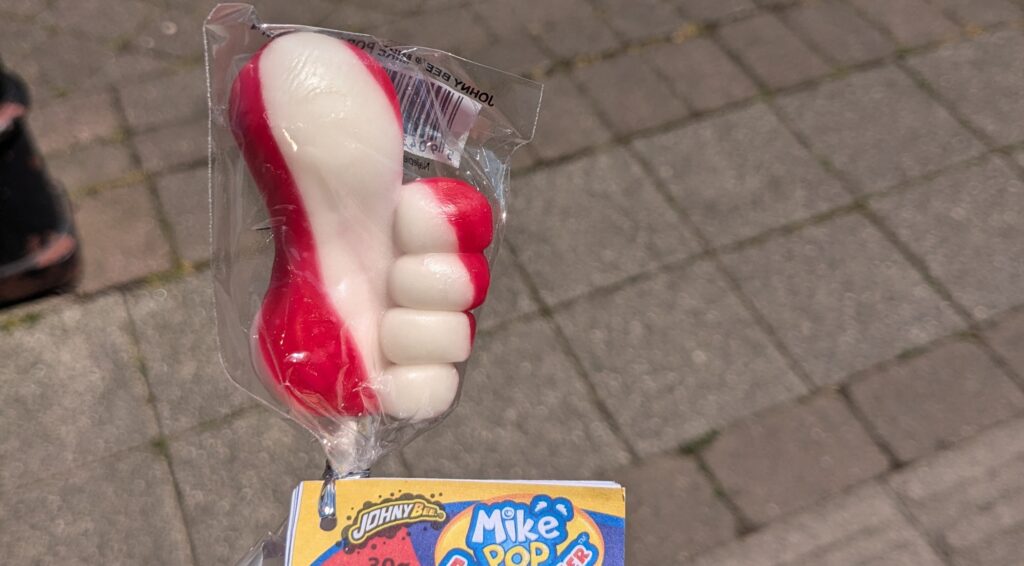 brightly coloured lollipop in the shape of a thumbs-up.